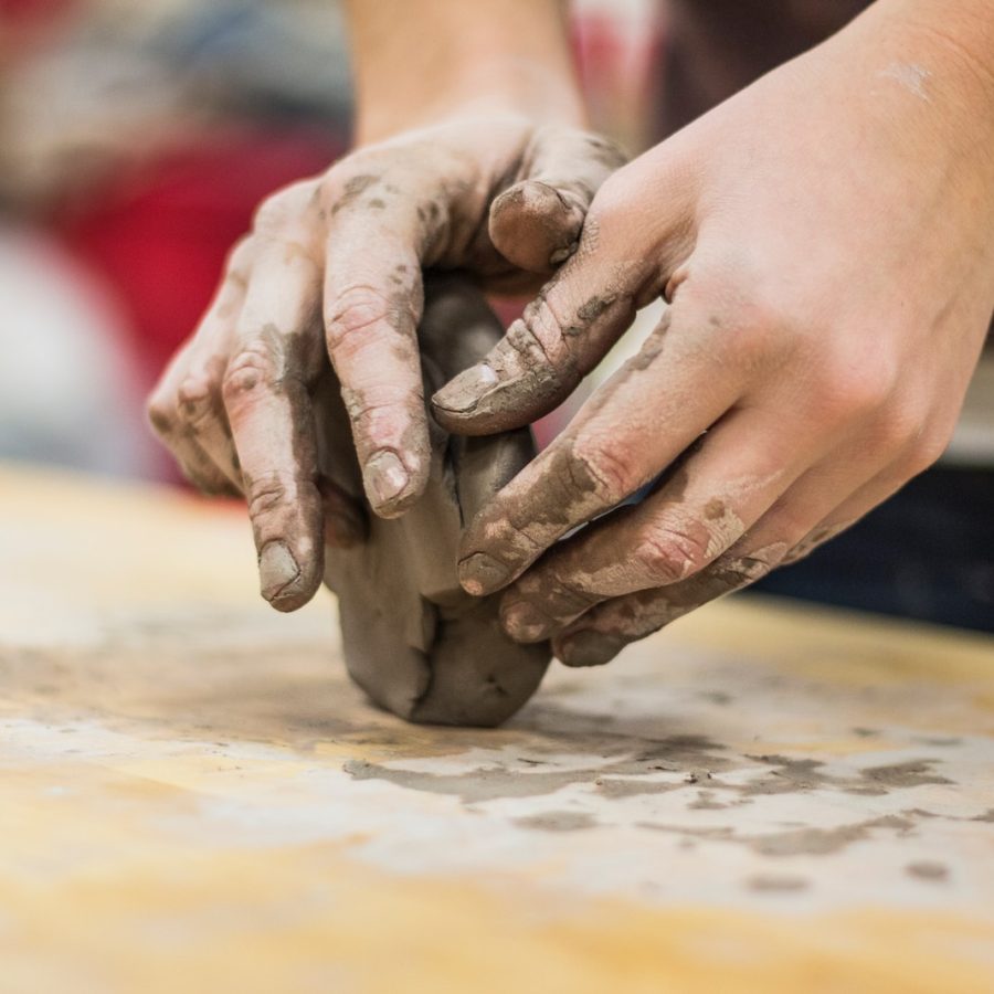 A clay stained hand of a potter engaging in a craft work of pottery or molding