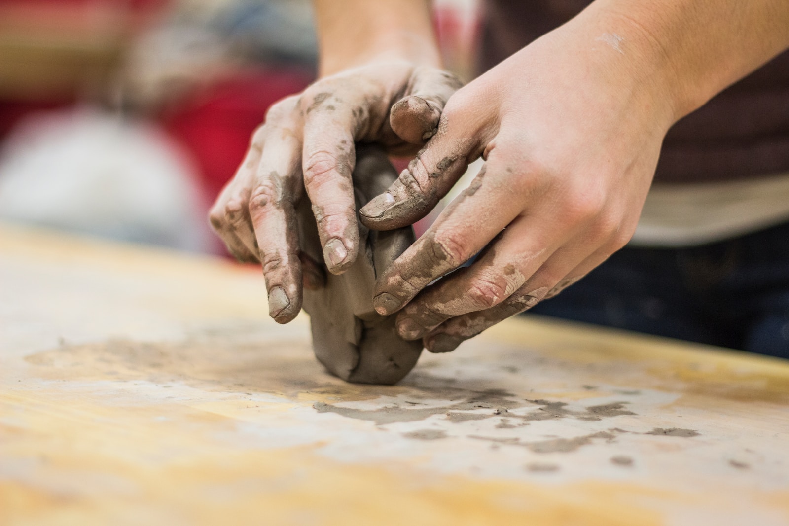 A clay stained hand of a potter engaging in a craft work of pottery or molding