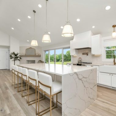 a large kitchen with a marble island and white cabinets