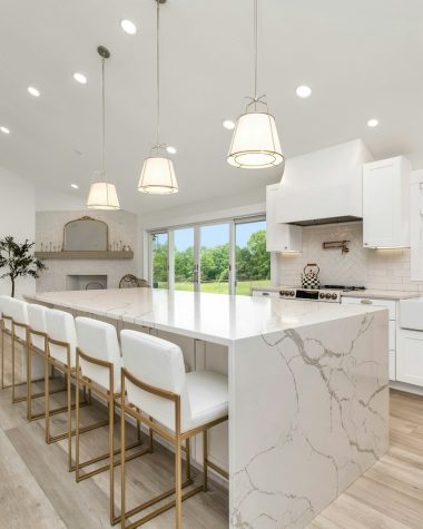 a large kitchen with a marble island and white cabinets