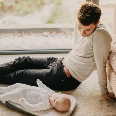 man in gray sweater lying on floor beside man in black shirt