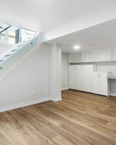 an empty room with a desk, computer, and stairs