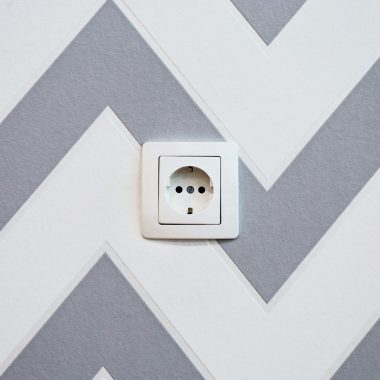 white power strip mounted on white and grey chevron painted wall