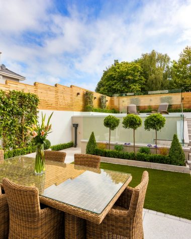 a patio with a table and chairs next to a fence