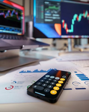 smartphone calculator on desk with financial charts behind