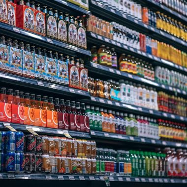 Verfblikken op een rek in een bouwmarkt met verschillende kleurenlabels en keurmerken zichtbaar