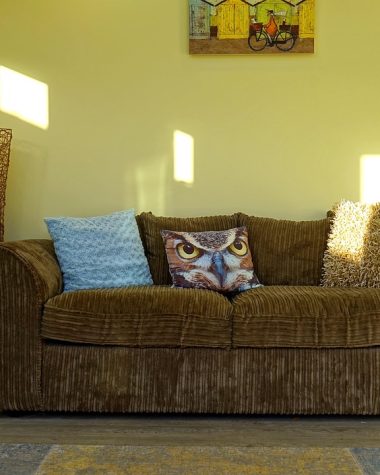 Woonkamer met een ribstof bank, geometrisch vloerkleed en gestreepte sierkussens in een evenwichtige patroonverdeling