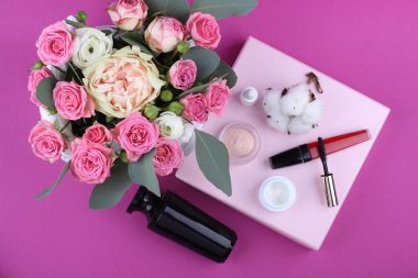 Huidverzorgingsproducten voor de herfst, waaronder een pot ceramide crème en een serum op een houten ondergrond