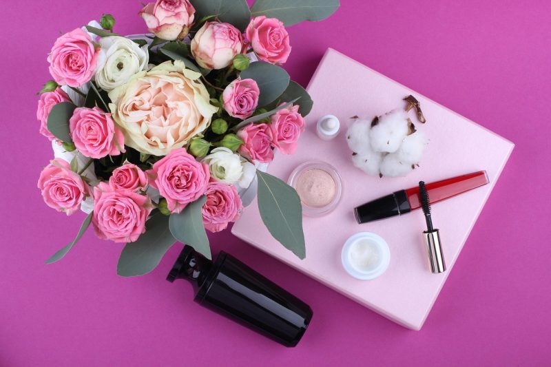 Huidverzorgingsproducten voor de herfst, waaronder een pot ceramide crème en een serum op een houten ondergrond