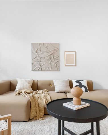 Designerkussen met jacquardpatroon op een linnen bank in een moderne woonkamer