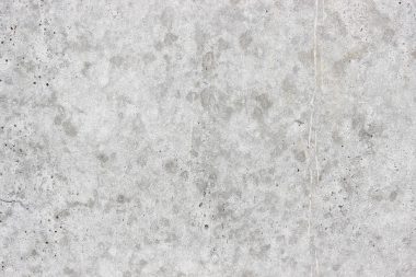 Drie grijze verfstalen in verschillende tinten op een witte muur, gefotografeerd met daglicht van opzij