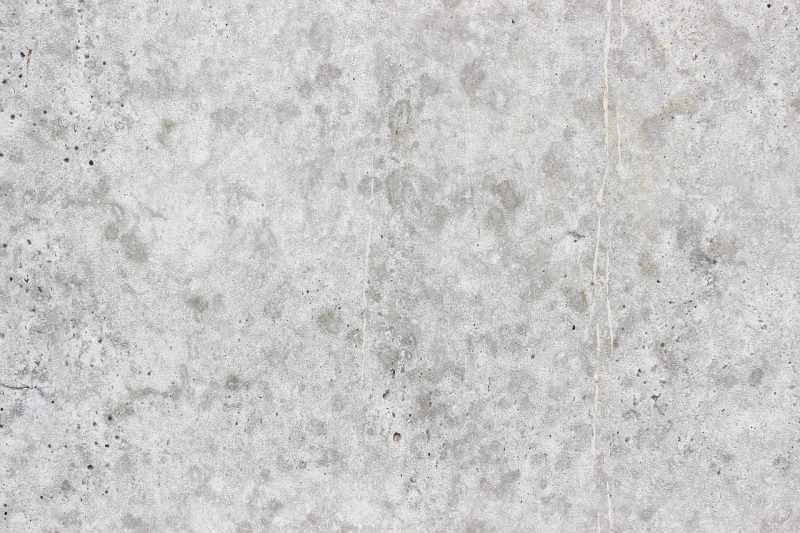 Drie grijze verfstalen in verschillende tinten op een witte muur, gefotografeerd met daglicht van opzij